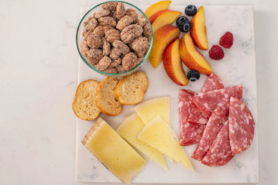 Marble board with cheese, peaches, flavored pecans and salami