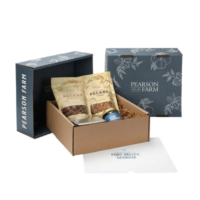 Gift box with bags of pecans, tin of chocolate, and jar of preserves.  Blue lids with the name Pearson Farm standing beside box
